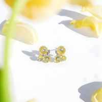 Yellow flower-shaped earrings on a white background with floral elements.