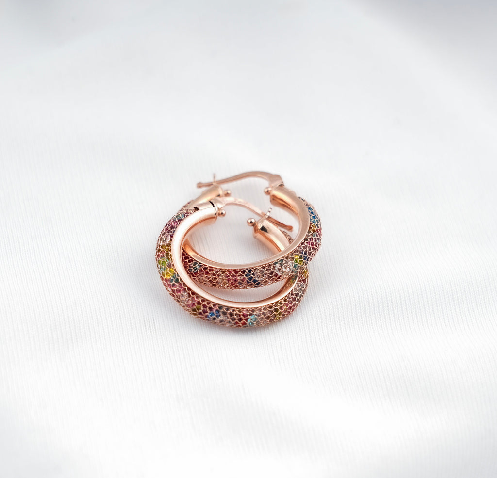 Rose gold hoop earrings with colorful gemstones on a light gray background