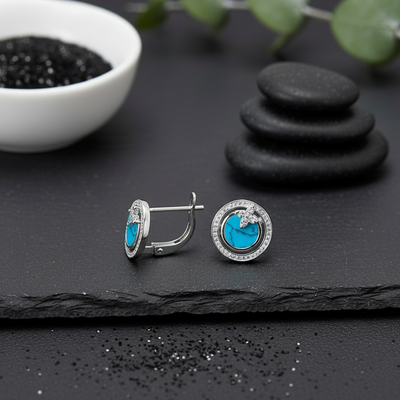 Pair of turquoise gemstone earrings on a dark surface with decorative elements. alternate view
