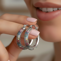 Close-up of a person holding colorful hoop earrings with a blurred background