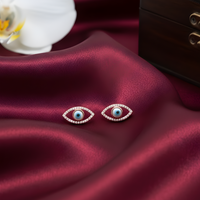 Pair of earrings on a burgundy fabric with a white orchid and wooden box in the background