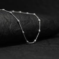 Silver neck chain against a dark background